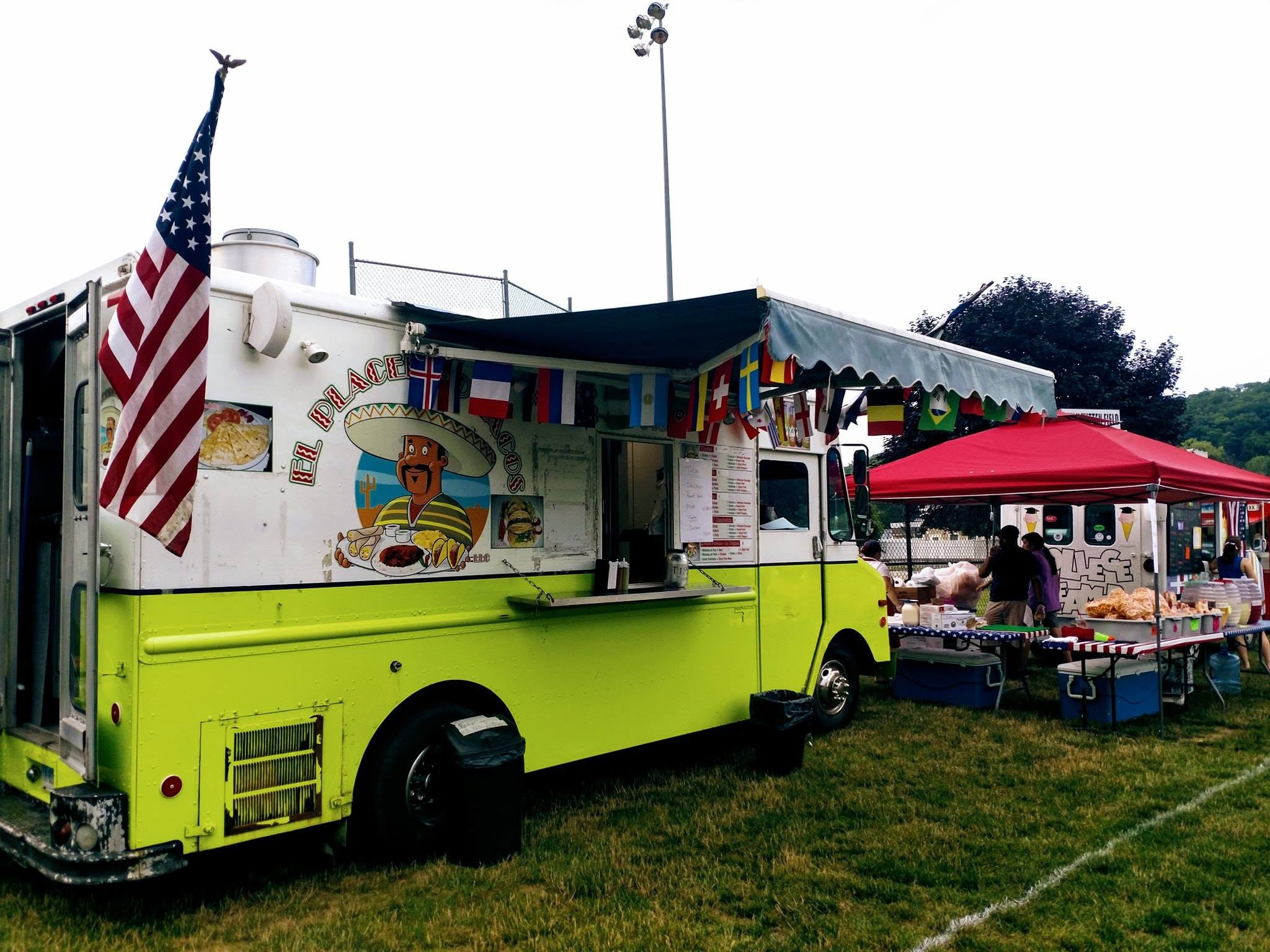 El Placerito Tacos Truck at a community event — US flag flying, serving the Norwalk crowd