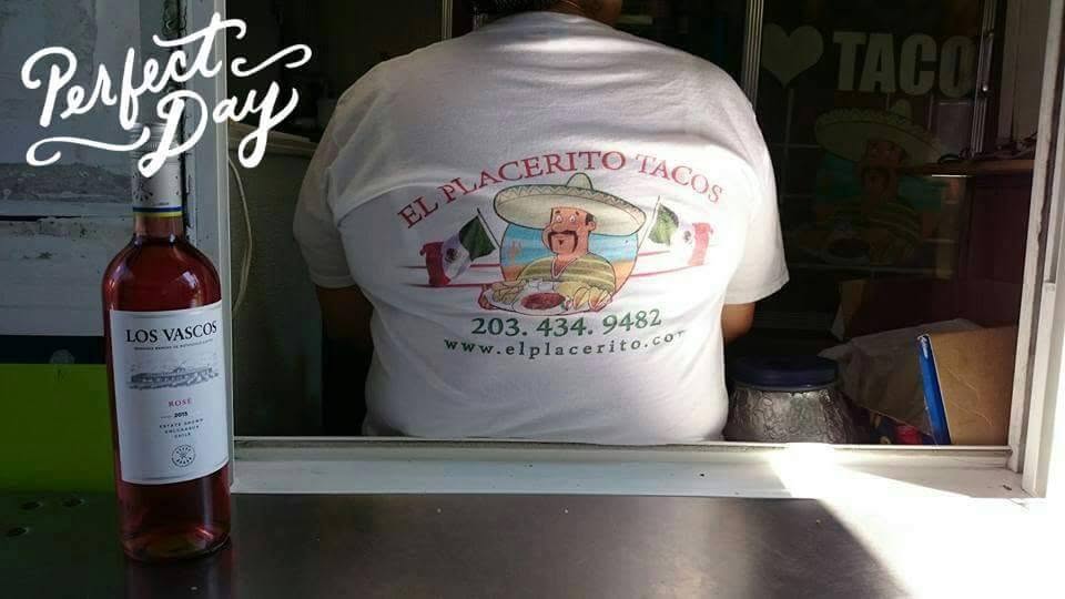 El Placerito Tacos — working the window, El Placerito shirt and the menu board visible